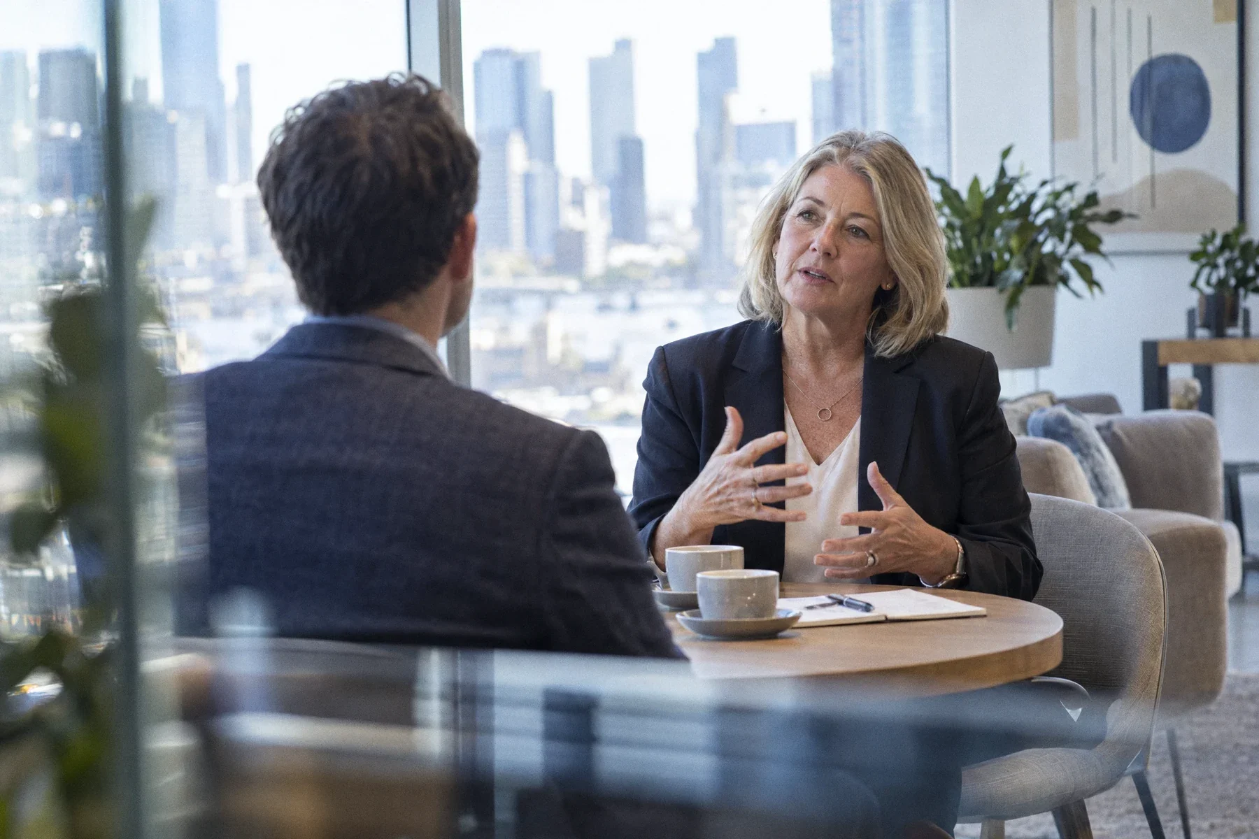 A senior executive talking with an adviser at a small table by a window